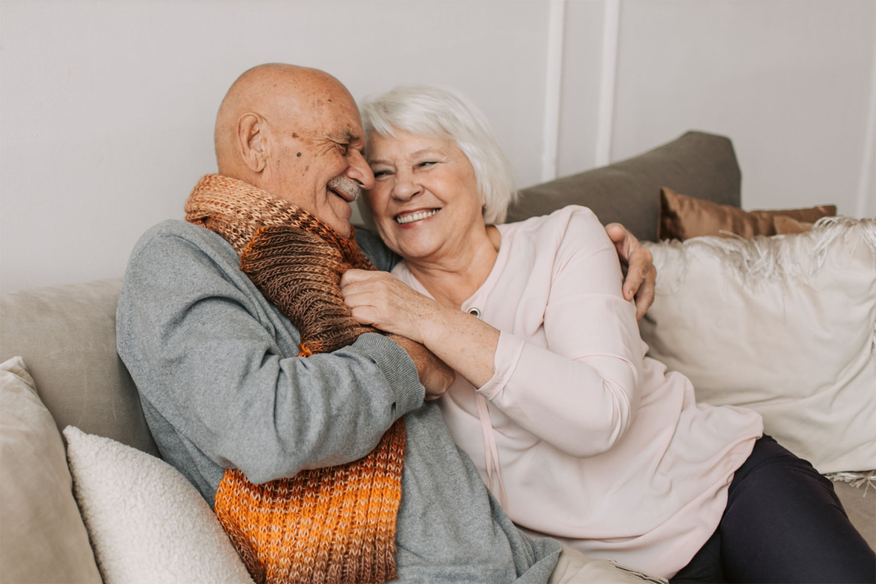 Older couple sitting on couch laughing together