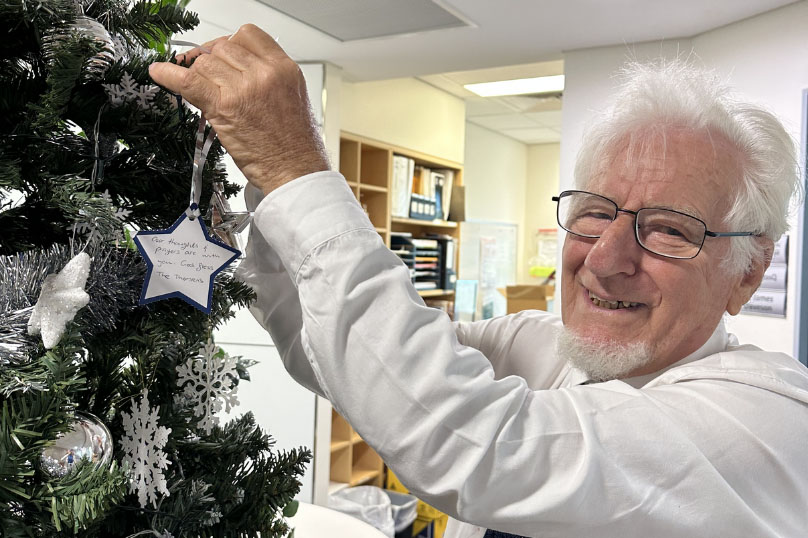 Volunteer putting decorations on a Christmas tree